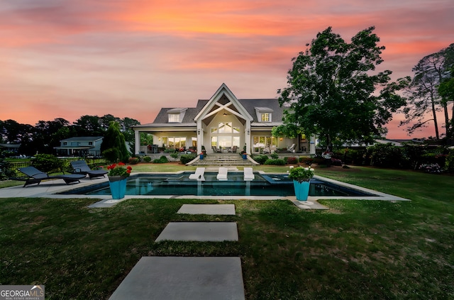 239 Lakeshore Cir, Milledgeville, GA 31061 - back of property at dusk with a lawn, fence, an outdoor pool, and a patio area