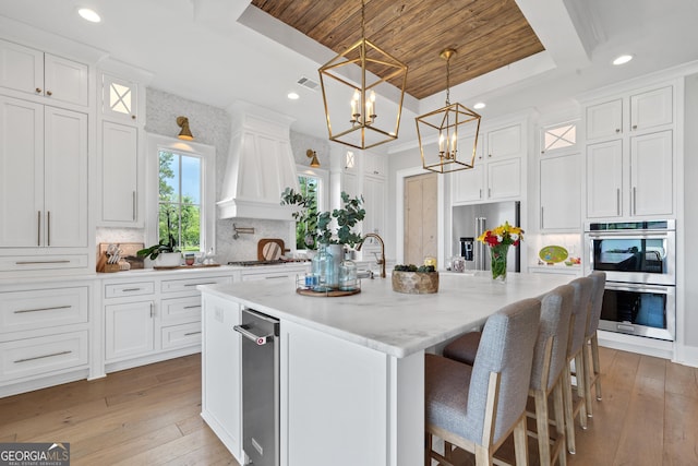 239 Lakeshore Cir, Milledgeville, GA 31061 - kitchen featuring a raised ceiling, stainless steel appliances, an island with sink, and white cabinets