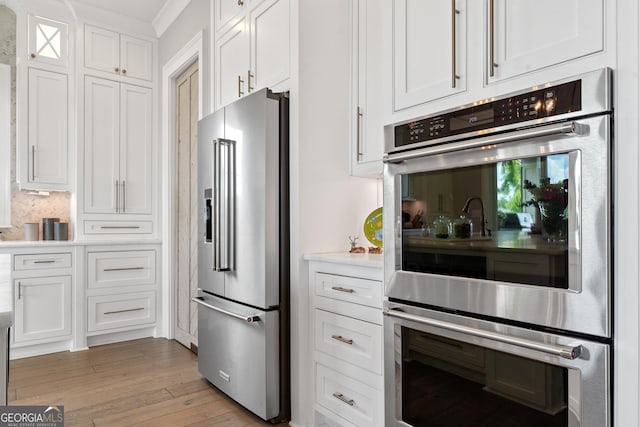 239 Lakeshore Cir, Milledgeville, GA 31061 - kitchen with light wood-type flooring, backsplash, white cabinetry, light countertops, and appliances with stainless steel finishes