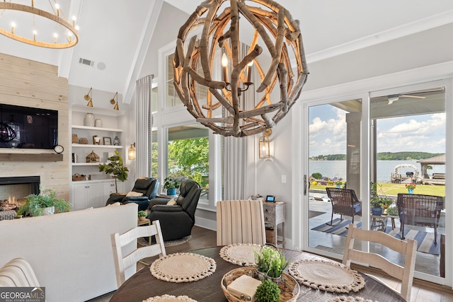 239 Lakeshore Cir, Milledgeville, GA 31061 - dining space featuring wood finished floors, an inviting chandelier, a water view, a fireplace, and visible vents