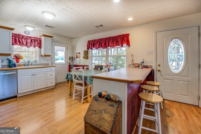 2000 Campbell Rd, Covington, GA 30014 - kitchen with stainless steel dishwasher, a kitchen bar, light wood-style floors, a peninsula, and healthy amount of natural light
