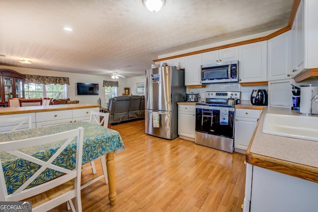 2000 Campbell Rd, Covington, GA 30014 - kitchen featuring appliances with stainless steel finishes, light countertops, white cabinets, open floor plan, and a textured ceiling