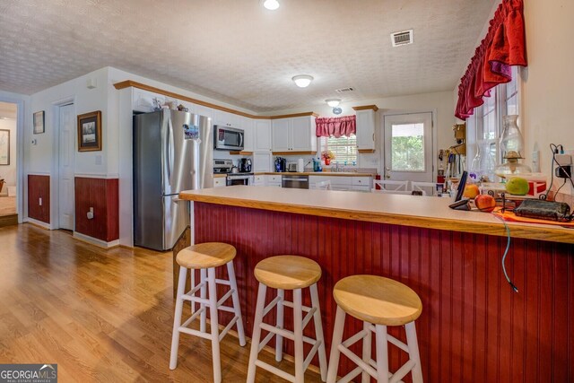 2000 Campbell Rd, Covington, GA 30014 - kitchen featuring stainless steel appliances, a peninsula, light wood-style floors, light countertops, and white cabinets