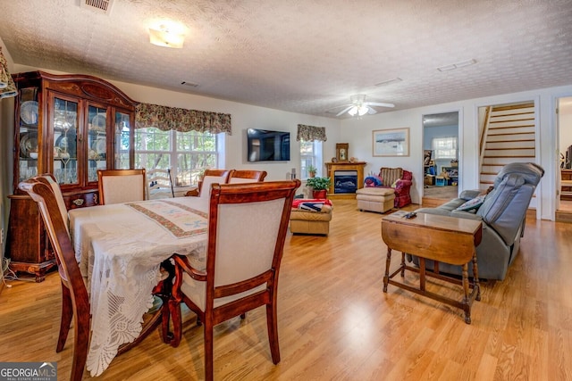 2000 Campbell Rd, Covington, GA 30014 - dining room featuring light wood-style floors, a ceiling fan, stairs, and a textured ceiling