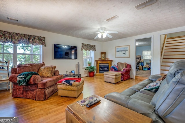 2000 Campbell Rd, Covington, GA 30014 - living room featuring light wood-style floors, stairway, ceiling fan, a textured ceiling, and a fireplace