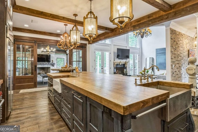 kitchen with a sink, an inviting chandelier, beam ceiling, butcher block counters, and open floor plan