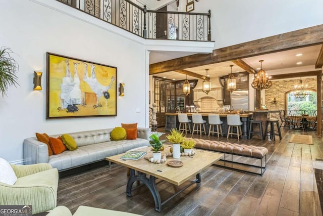 living area featuring a chandelier, beamed ceiling, and dark wood finished floors