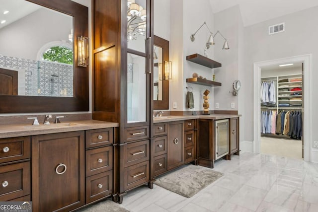 full bathroom featuring vanity, wine cooler, a walk in closet, visible vents, and vaulted ceiling
