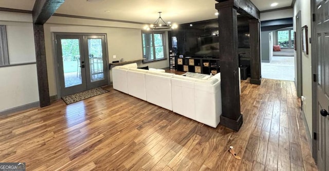 living area with wood finished floors, french doors, and crown molding