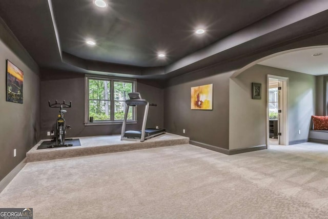 exercise room with recessed lighting, arched walkways, carpet, baseboards, and a raised ceiling