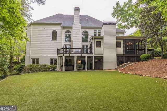 back of house featuring a sunroom, a deck, a lawn, and a chimney