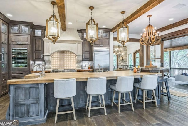 kitchen with a chandelier, a large island with sink, beamed ceiling, and a sink