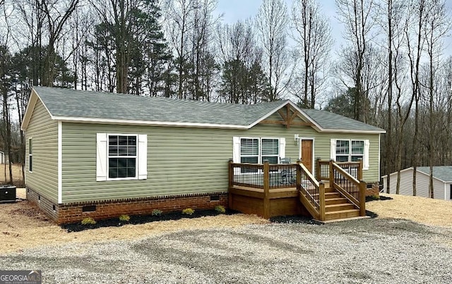 manufactured / mobile home with crawl space, a deck, and a shingled roof