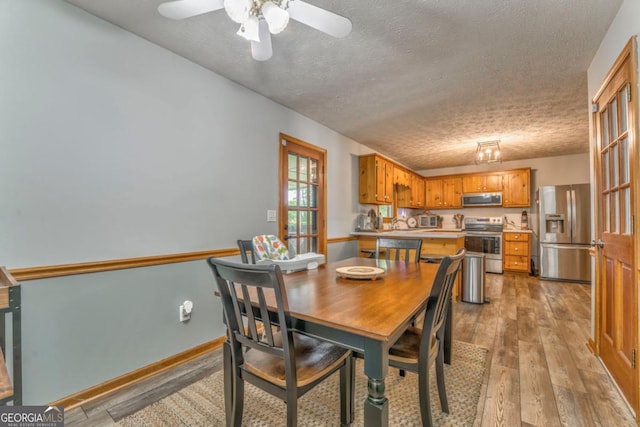 dining area featuring a ceiling fan, a textured ceiling, and light wood-style flooring