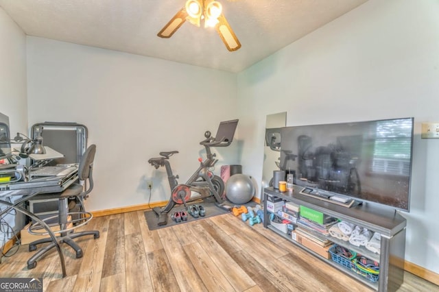 interior space with wood finished floors, a ceiling fan, and baseboards