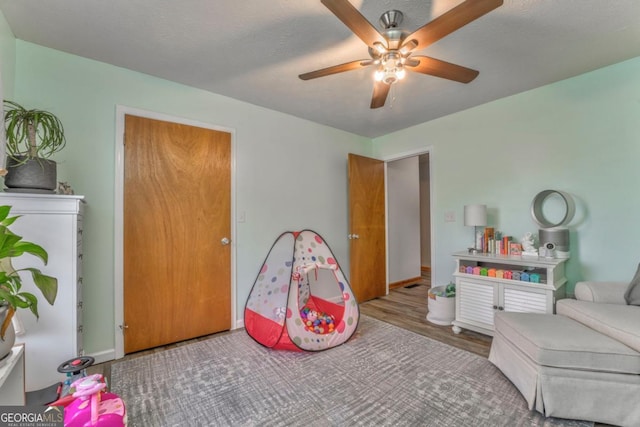 recreation room with wood finished floors and a ceiling fan