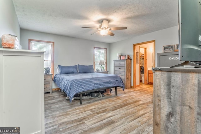 bedroom with a textured ceiling, light wood-type flooring, and a ceiling fan