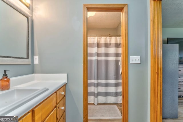 bathroom featuring curtained shower, a textured ceiling, and vanity