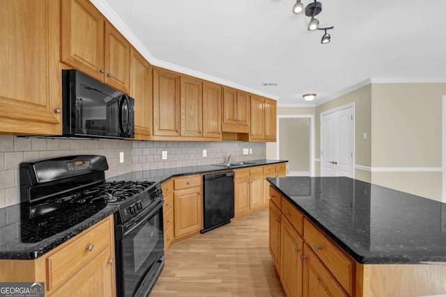 kitchen with light wood-style floors, a center island, tasteful backsplash, a sink, and black appliances