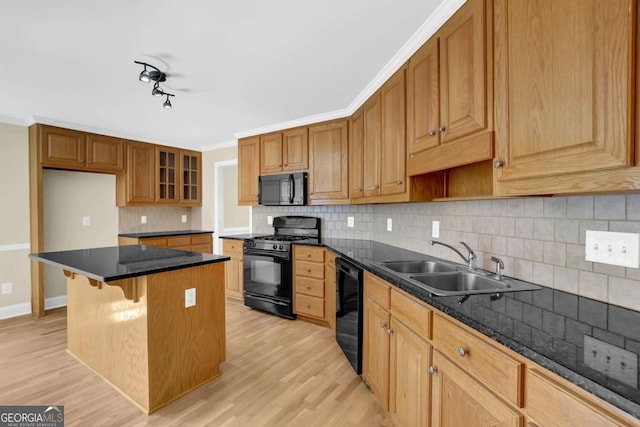 kitchen featuring light wood-style floors, a sink, black appliances, and a center island