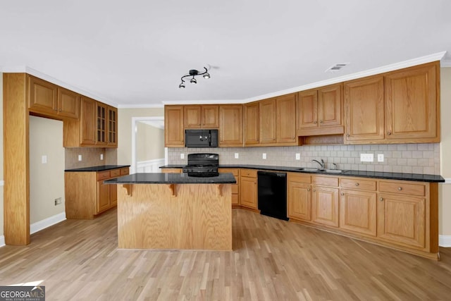 kitchen featuring dark countertops, light wood-style flooring, tasteful backsplash, visible vents, and black appliances