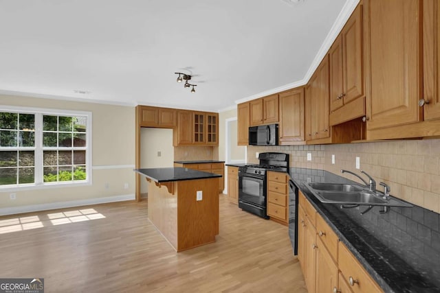 kitchen featuring decorative backsplash, a kitchen island, light wood-type flooring, a sink, and black appliances