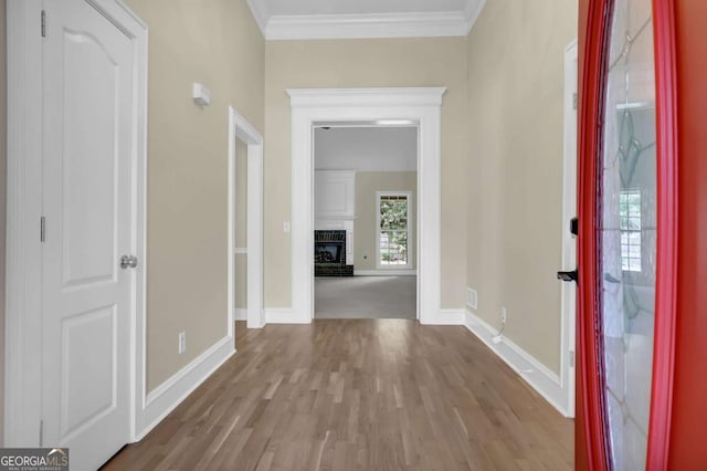 foyer featuring baseboards, ornamental molding, a fireplace, and wood finished floors