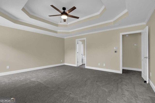 spare room featuring dark carpet, a ceiling fan, a tray ceiling, and ornamental molding