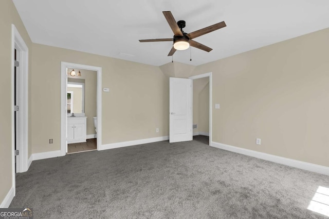 unfurnished bedroom with baseboards, a ceiling fan, dark colored carpet, and connected bathroom