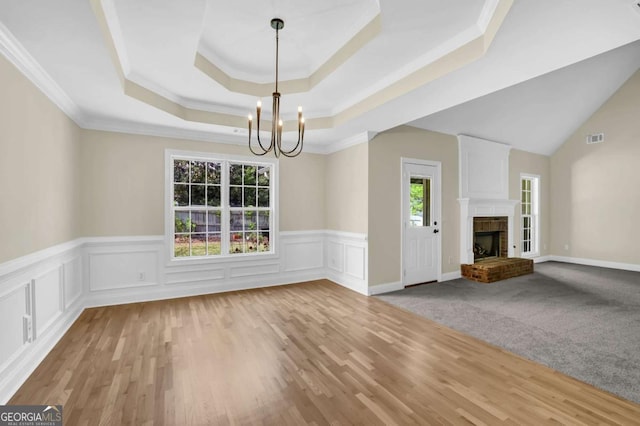 unfurnished dining area with a notable chandelier, wainscoting, a fireplace, wood finished floors, and visible vents
