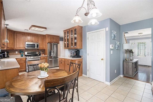 10 Callaway Ct, Hiram, GA 30141 - kitchen with stainless steel appliances, glass insert cabinets, brown cabinetry, light countertops, and a textured ceiling