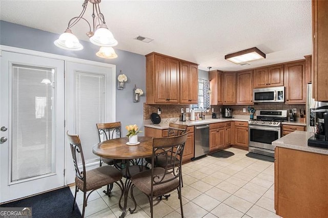 10 Callaway Ct, Hiram, GA 30141 - kitchen featuring appliances with stainless steel finishes, decorative backsplash, light tile patterned floors, light countertops, and decorative light fixtures
