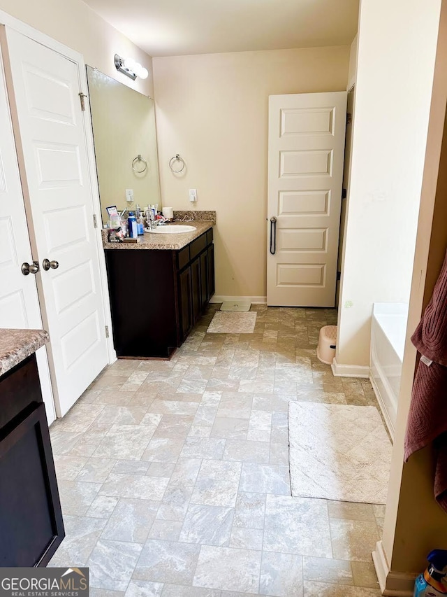 573 Emporia Loop, Mcdonough, GA 30253 - bathroom featuring baseboards, vanity, and stone finish flooring