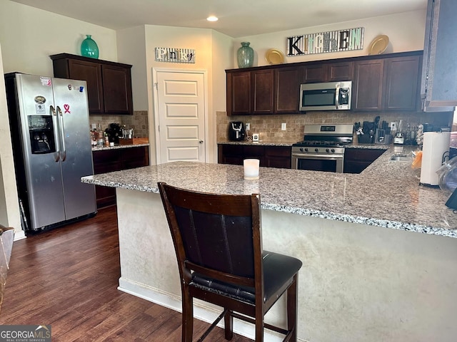 573 Emporia Loop, Mcdonough, GA 30253 - kitchen with backsplash, stainless steel appliances, light stone countertops, and dark brown cabinets