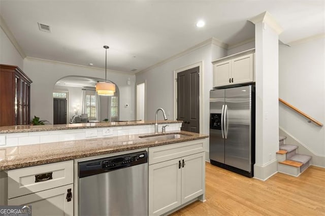 kitchen with crown molding, appliances with stainless steel finishes, a sink, light wood-style floors, and visible vents