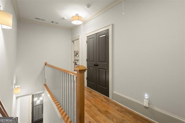 hallway featuring an upstairs landing, ornamental molding, wood finished floors, and visible vents