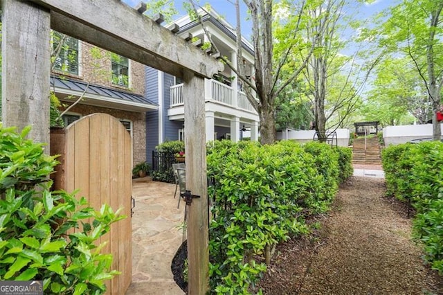 719 Hammond Dr, Woodstock, GA 30188 - view of side of property featuring a standing seam roof, a gate, a balcony, and a metal roof