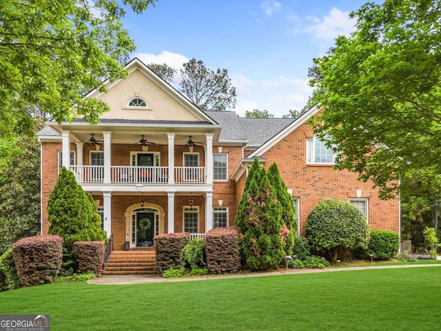 neoclassical home featuring ceiling fan, a front lawn, and brick siding