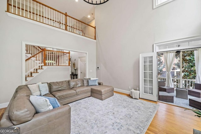 living area with stairway, baseboards, a high ceiling, and wood finished floors
