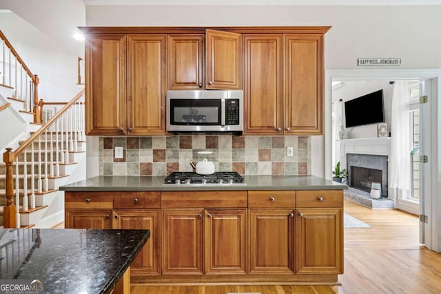 kitchen featuring decorative backsplash, dark stone counters, appliances with stainless steel finishes, and brown cabinets