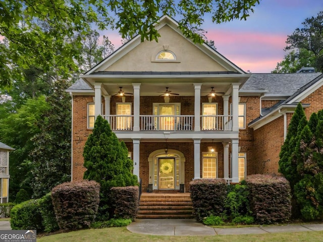 neoclassical home with a porch, stucco siding, a balcony, and brick siding