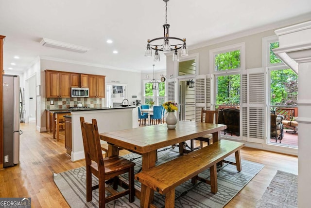 dining room with an inviting chandelier, recessed lighting, crown molding, and light wood-type flooring