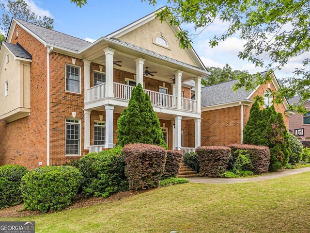 neoclassical / greek revival house featuring brick siding, a front lawn, ceiling fan, and a balcony