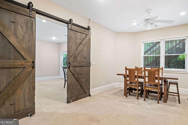 dining area featuring baseboards, a barn door, plenty of natural light, and light carpet