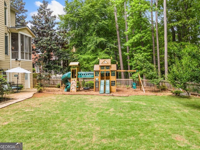 view of playground with a lawn, a fenced backyard, and a sunroom