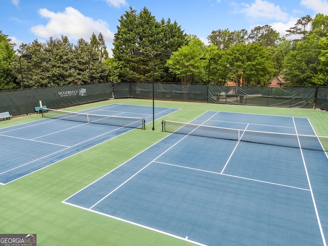 view of tennis court featuring community basketball court and fence