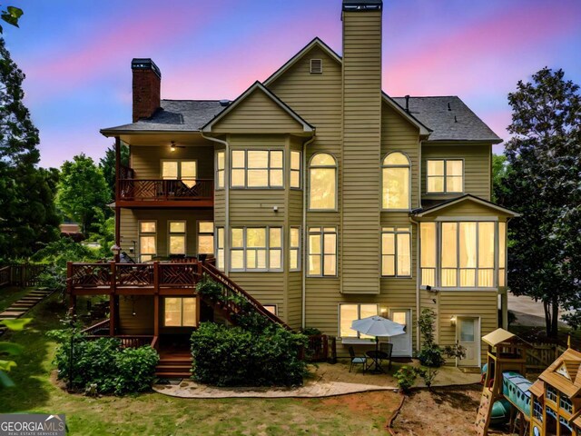 back of property featuring a chimney, a deck, a patio area, stairway, and a balcony
