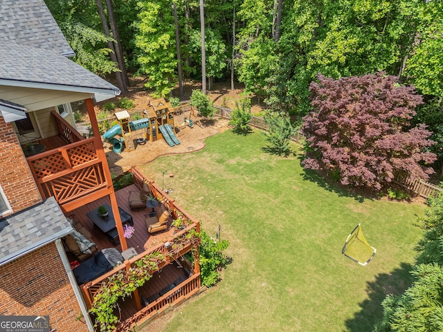 view of yard featuring a playground, fence, and a wooden deck