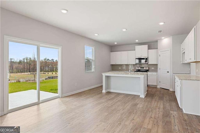kitchen with white cabinetry, light wood-type flooring, stainless steel appliances, and baseboards