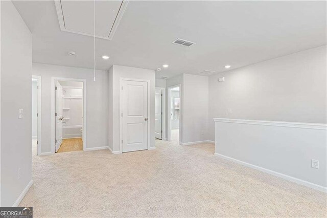 spare room with light colored carpet, visible vents, baseboards, attic access, and recessed lighting